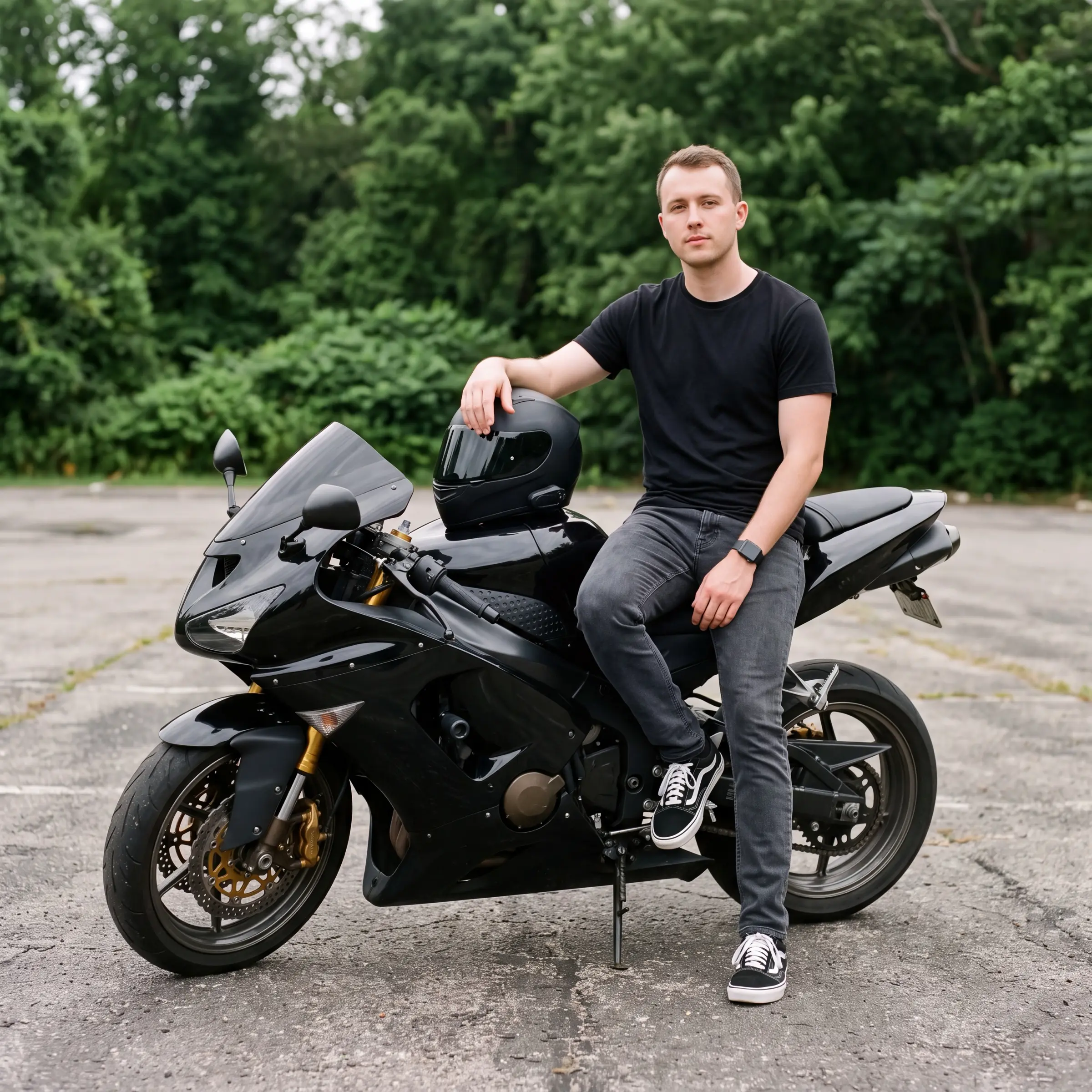 Man sitting on a black sport motorcycle with a helmet resting on the tank